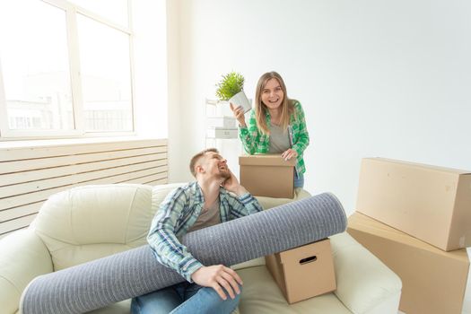 Satisfied cheerful young couple strong man and pretty woman holding their things in their hands sitting in the living room of a new apartment. Housewarming concept