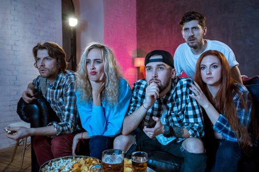 Group of friends watching TV match at home. Football fans on the couch