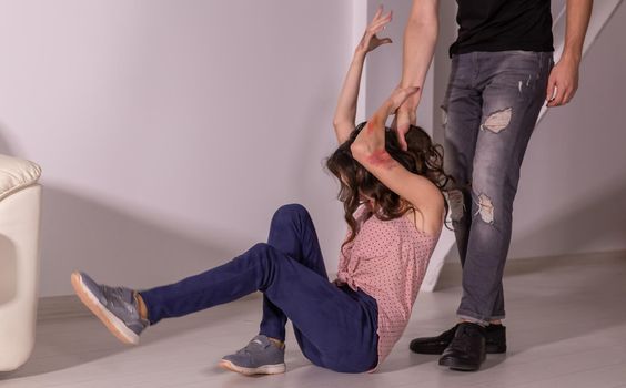 Domestic violence, abuse and victim concept - aggressive man dragging helpless woman by hair.