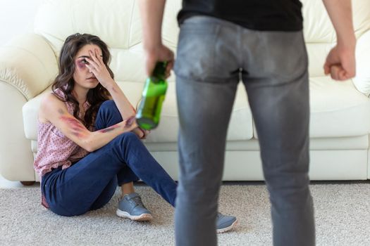 domestic violence, alcoholic and abuse concept - drunk man with bottle abusing his wife lying on the floor.