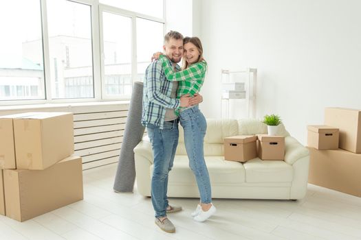 Loving young couple embracing rejoicing in moving to their new home. The concept of moving and housewarming of young family