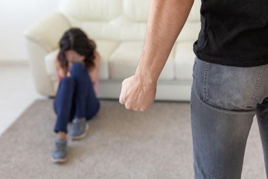 Victim, domestic violence and abuse concept - man threatening with fist to crying woman on floor scared and terrified in domestic violence.