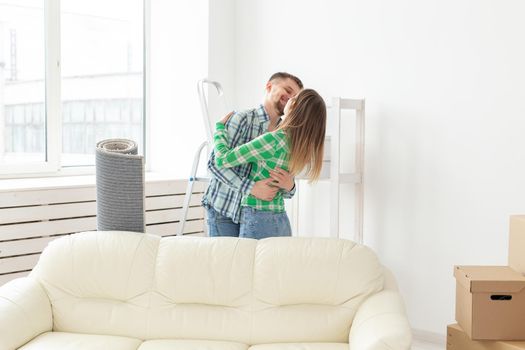 Unidentified young couple embraces and dances in the living room of their new apartment. The concept of affordable mortgage and new housing for a young family