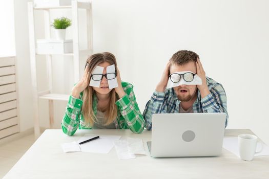 Young upset husband and wife were upset because of numerous expenses on paying for housing and communal services and repairing the apartment. covering their eyes with checks and ears with their hands