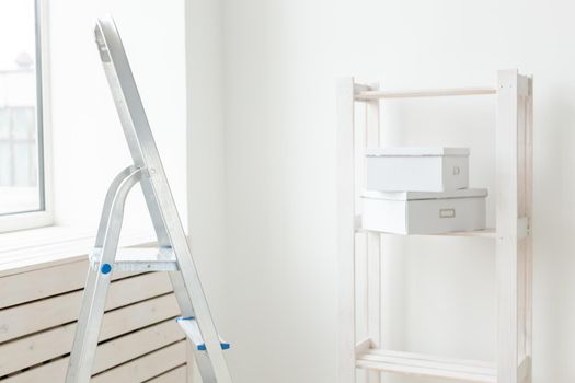 Stepladder and an empty shelf with boxes are in the new living room during the renovation after the move. The concept of housewarming and repair in new housing