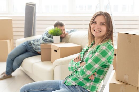 Positive smiling young girl sitting against her laughing blurred husband in a new living room while moving to a new home. The concept of joy from the possibility of finding new housing