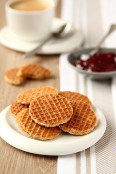 Mini stroopwafels (syrupwaffles) on a plate with cup of coffee and jam