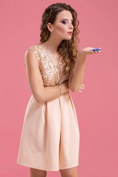 Beautiful young woman in dress with casino chips in the hands on pink background. Casino. Emotions. Gambling