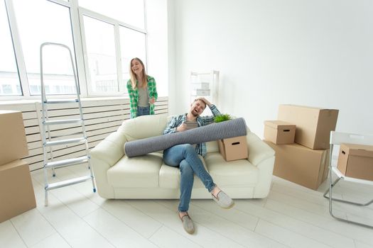 Positive crazy cheerful couple rejoices in moving their new apartment sitting in the living room with their belongings. Concept of housewarming and mortgages for a young family