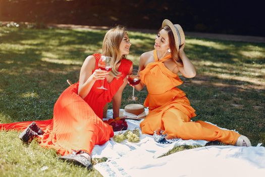 Beautiful girl in a red dress. Women sitting in a summer park.