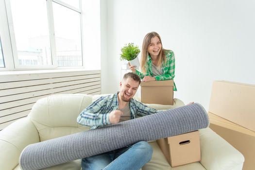 Satisfied cheerful young couple strong man and pretty woman holding their things in their hands sitting in the living room of a new apartment. Housewarming concept