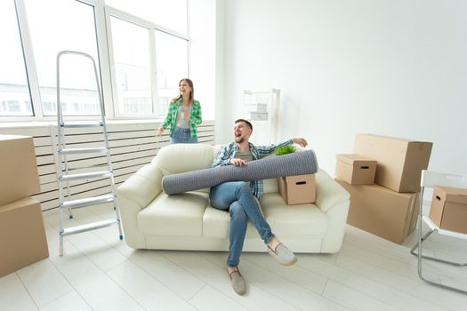 Positive crazy cheerful couple rejoices in moving their new apartment sitting in the living room with their belongings. Concept of housewarming and mortgages for a young family