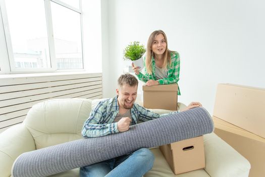 Satisfied cheerful young couple strong man and pretty woman holding their things in their hands sitting in the living room of a new apartment. Housewarming concept