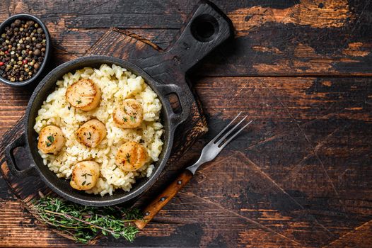 Seafood Risotto with Scallops in a pan. Dark wooden background. Top view. Copy space.