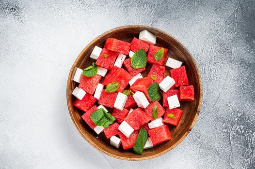 Watermelon Salad with feta cheese in a wooden plate. White background. Top view.