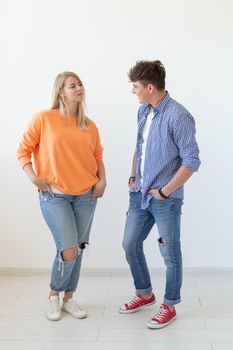 Portrait of a cheerful young positive couple in full growth dressed in casual clothes posing on a white background. Concept of stylish young modern people