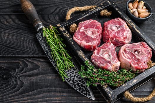 Raw lamb neck meat on a butcher table with knife. Black wooden background. Top view. Copy space.