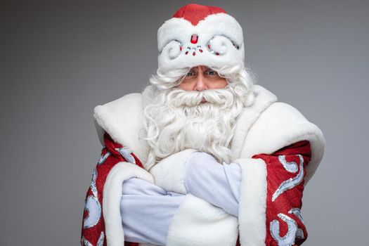 Serious Santa Claus crossed his arms over his chest and dissatisfied, studio portrait on gray background. High quality photo