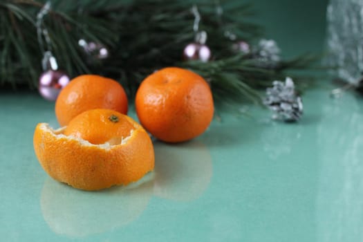 mandarins three lie next to the will of the Christmas tree on a green background. festive atmosphere.