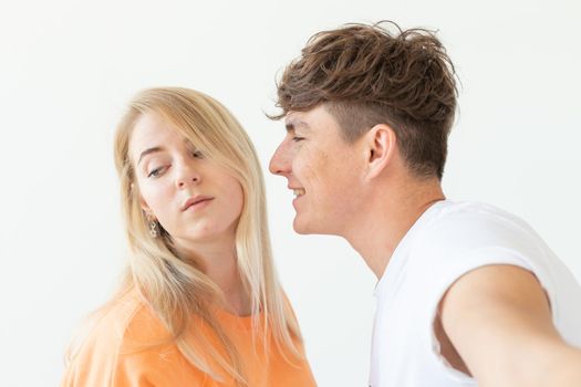 Charming young couple cute blond girl girl take a selfie posing over white background. Concept a young couple of teenagers or millennials In love