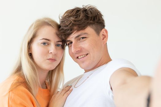 Portrait of a cute positive cheerful young couple of students taking selfie on a smartphone or camera. The concept of a passionate young couple in love with students