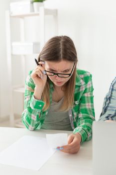 Upset young woman considers the amount of expenses for purchases and payment of credits by entering information into laptop for accounting of home bookkeeping. Concept of savings and waste