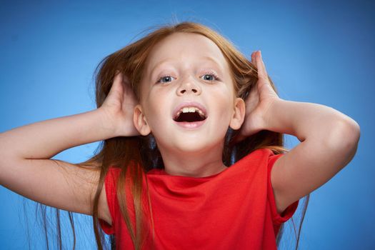 cheerful cute red-haired girl childhood blue background. High quality photo