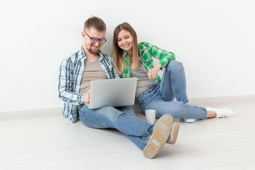 Charming young woman and a smiling man are watching online stores using a laptop to buy plumbing in a new apartment. Housewarming and repair concept. Copyspace