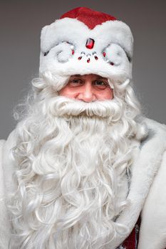 Stock photo of white-bearded Father Frost in red and white hat and traditional costume with red mittens showing both thumbs up.