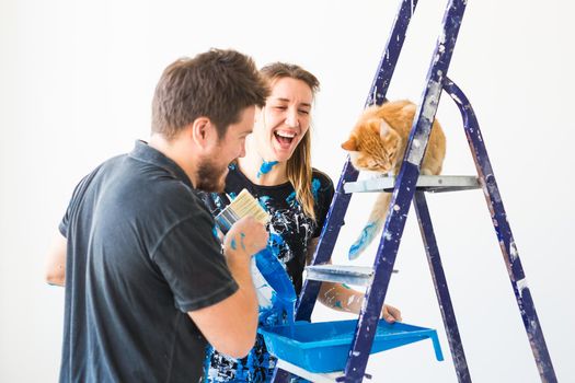 People, redecoration and renovation concept - portrait of couple with cat pour paint.