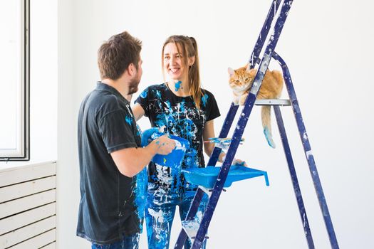 Teamwork and repair concept - young couple with cat doing a renovation in new apartment.