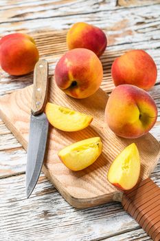 Fresh Peaches, organic fruit on the chopping Board. White wooden background. Top view.
