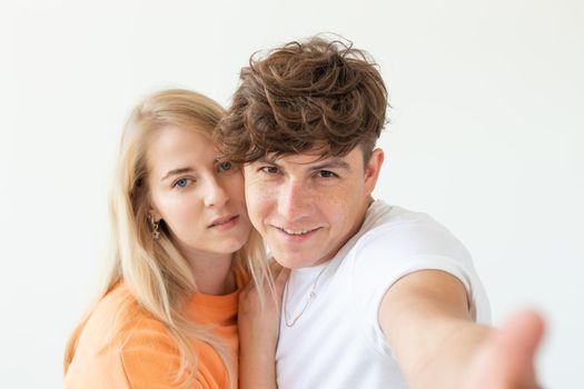 Portrait of a cute positive cheerful young couple of students taking selfie on a smartphone or camera. The concept of a passionate young couple in love with students