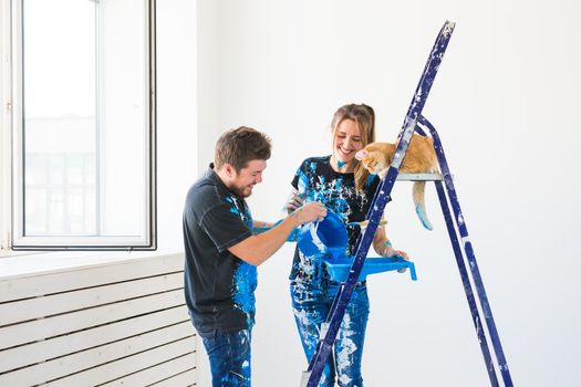 Teamwork and repair concept - young couple with cat doing a renovation in new apartment.