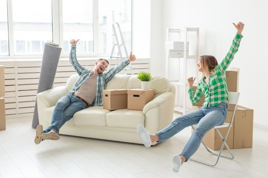 Positive smiling young girl sitting against her laughing in a new living room while moving to a new home. The concept of joy from the possibility of finding new housing