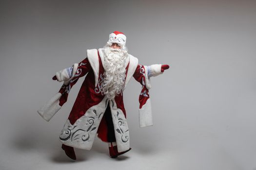 Stock photo of smiling happy Santa in traditional hat with rhinestones and long white beard looking at camera. Cutout on red background. Happiness concept.