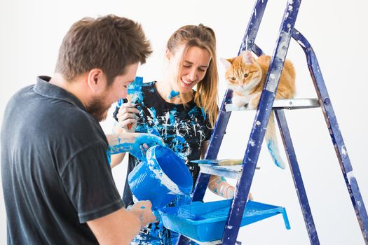 Teamwork and repair concept - young couple with cat doing a renovation in new apartment.