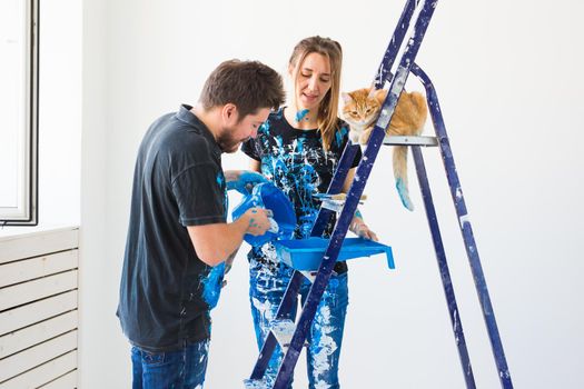 Teamwork and repair concept - young couple with cat doing a renovation in new apartment.