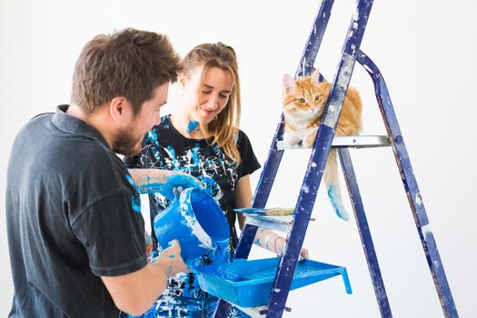 Teamwork and repair concept - young couple with cat doing a renovation in new apartment.