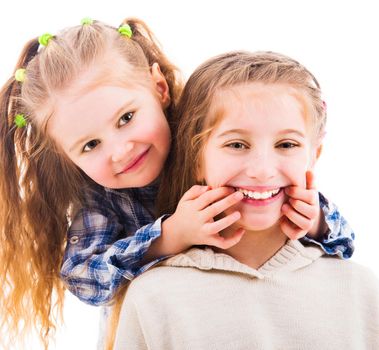 Little girl using her fingers to make her older sister smile isolated on white background