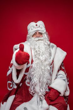 Stock photo of smiling happy Santa in traditional hat with rhinestones and long white beard looking at camera. Cutout on red background. Happiness concept.