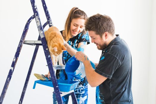 People, redecoration and renovation concept - portrait of couple with cat pour paint.