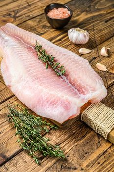 Raw fillet of pangasius fish on a cutting board. Wooden background. Top view.