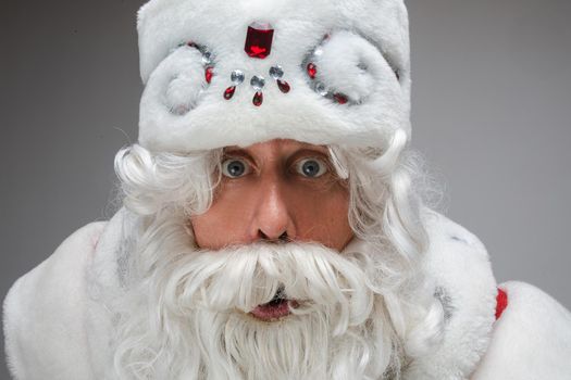 Close up portrait of studio surprised shocked Santa Claus on gray background, candid emotions, body language. High quality photo