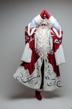 Stock photo of smiling happy Santa in traditional hat with rhinestones and long white beard looking at camera. Cutout on red background. Happiness concept.