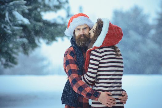 Christmas couple of happy man and woman. Couple in love with red santa claus hat in winter outdoor. Winter holiday and vacation.