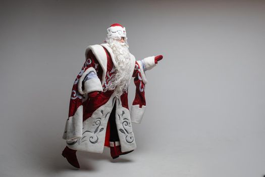 Stock photo of smiling happy Santa in traditional hat with rhinestones and long white beard looking at camera. Cutout on red background. Happiness concept.