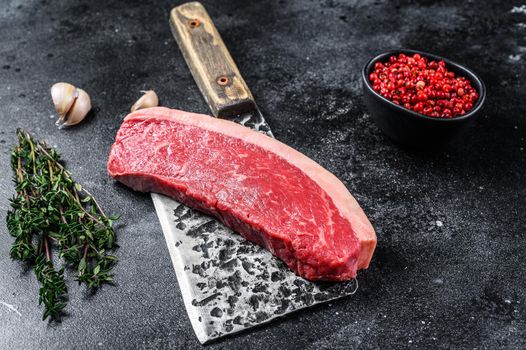 Fresh Raw top sirloin beef meat steak on a butcher cleaver. Dark wooden background. Top view.