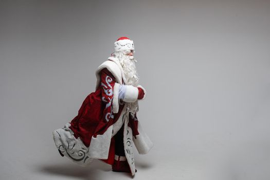 Stock photo of smiling happy Santa in traditional hat with rhinestones and long white beard looking at camera. Cutout on red background. Happiness concept.