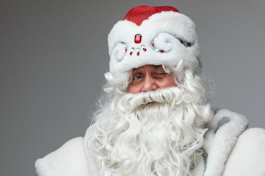 Stock photo of smiling happy Santa in traditional hat with rhinestones and long white beard looking at camera. Cutout on red background. Happiness concept.